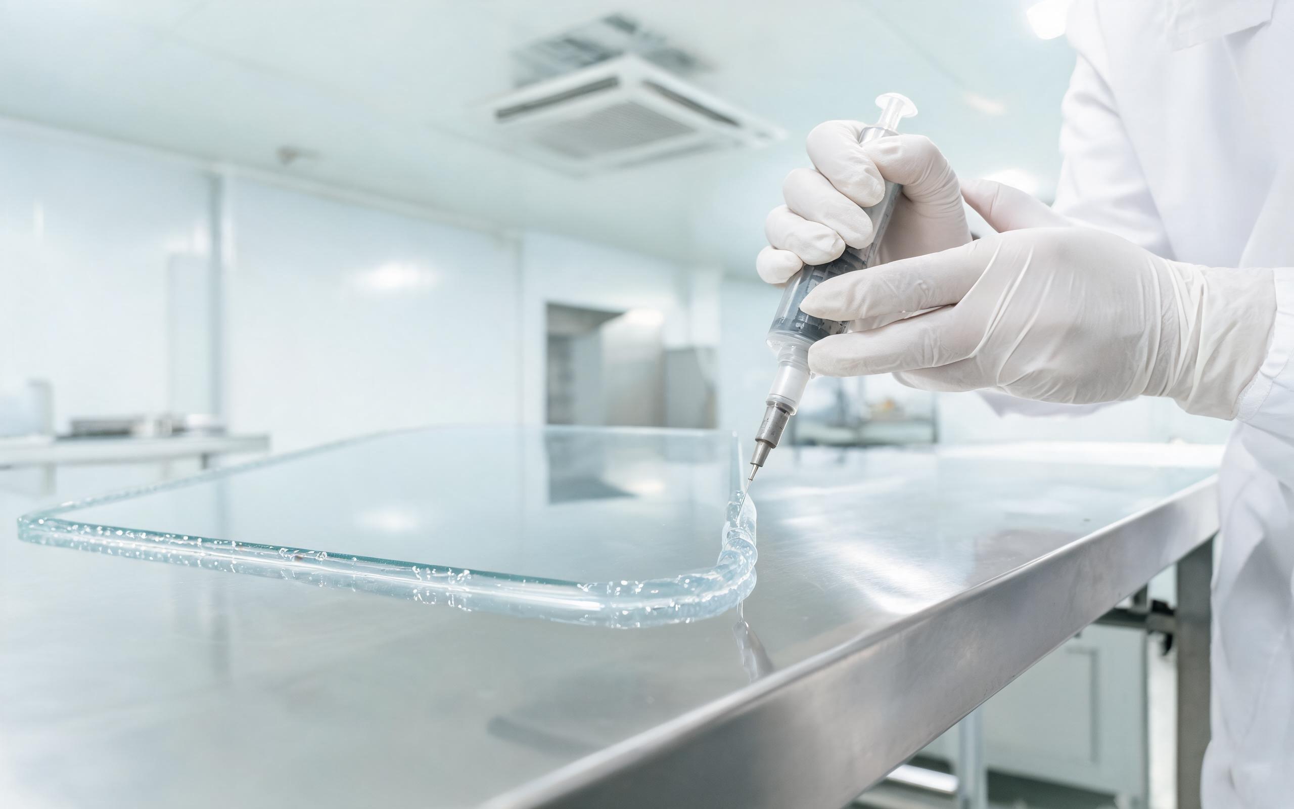 Silicone gel dispense on cover glass technician dispensing silicone gel optical resin for industrial panel pc optical bonding on a cleanroom bench